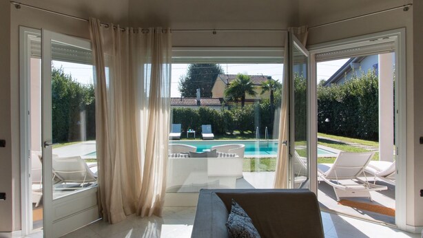 A modern living room with a large sliding glass door leading to a pool area.