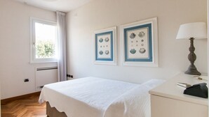 A bedroom with a bed, a bedside table, a lamp, and framed pictures on the wall.