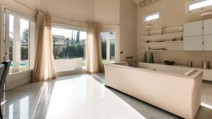A spacious room with a large window, a sofa, and a cabinet with decorative items.