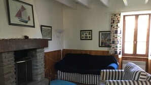 A cozy living room with a fireplace, striped furniture, and framed pictures on the walls. - houses / villas - 3 rooms - 4 persons (Groix)
