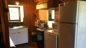 A compact kitchen with white cabinets, a stove, a microwave, and a refrigerator. - houses / villas - 3 rooms - 4 persons (Groix)