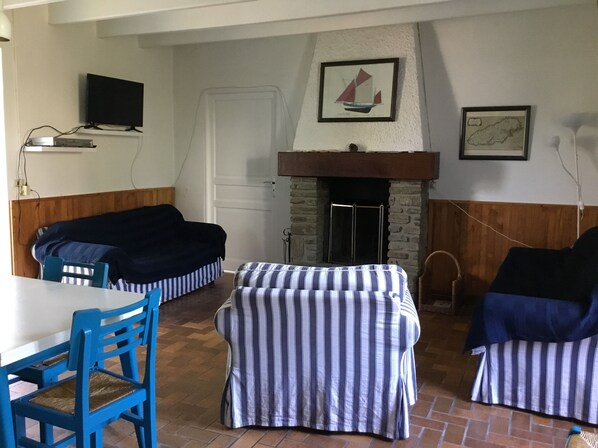 A cozy room with a fireplace, striped cushions, a television, and a map on the wall. - houses / villas - 3 rooms - 4 persons (Groix)