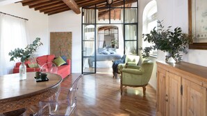 A spacious living area with a wooden ceiling, a red sofa, a green armchair, and a dining table with chairs. - Apartment The basket of the Angels, Florence amazing views (Firenze)