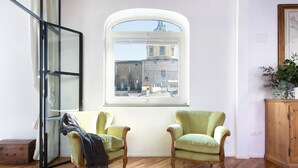 A room with two green armchairs, a wooden cabinet, and a window with a view of a building. - Apartment The basket of the Angels, Florence amazing views (Firenze)
