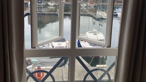 A bay with boats docked, a view of buildings, and a railing with a safety sign. - Fabulously Located Marina Apartment - Superb Waterside Views from every window. (Eastbourne)