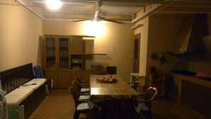 Een eetruimte met een tafel, stoelen, een bank en een plafondventilator.
