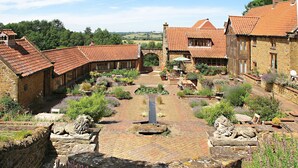 Ein Innenhof mit Steinmauern, einer zentralen Wasserspielanlage und umliegender Bepflanzung.