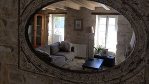 Ein rustikaler Raum mit Steinwand, Holzschrank, Sofa, Tisch und einer Lampe.