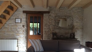 Ein gemütliches Zimmer mit Steinwand, Holztür, einer Couch, einem Spiegel und einer Lampe.