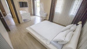Um quarto espaçoso com uma cama grande, uma televisão na parede e uma poltrona com dossel.