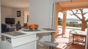A modern living room with a TV, seating, and a balcony with a view. - VILLA 4 ROOMS 3 BATHROOMS WITH  HEATED POOL  500M SEA VIEW / MOUNTAIN (Zonza)