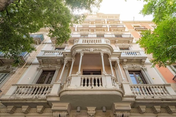 Um edifício de vários andares com varandas ornamentadas e detalhes arquitetônicos clássicos.