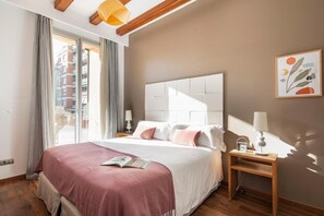 Quarto de hotel moderno com uma cama grande, uma mesa de cabeceira com luminária e vista para a cidade pela janela.