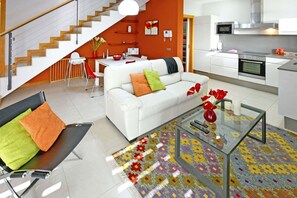 Uma sala de estar moderna com um sofá branco, uma mesa de centro de vidro e um tapete colorido.