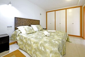 A bedroom with a bed, a nightstand, a wardrobe, and a wall-mounted light fixture. - Salobre Vista Golf 19 (Maspalomas)