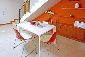 A modern kitchen with a white table, red chairs, and a staircase. - Salobre Vista Golf 19 (Maspalomas)