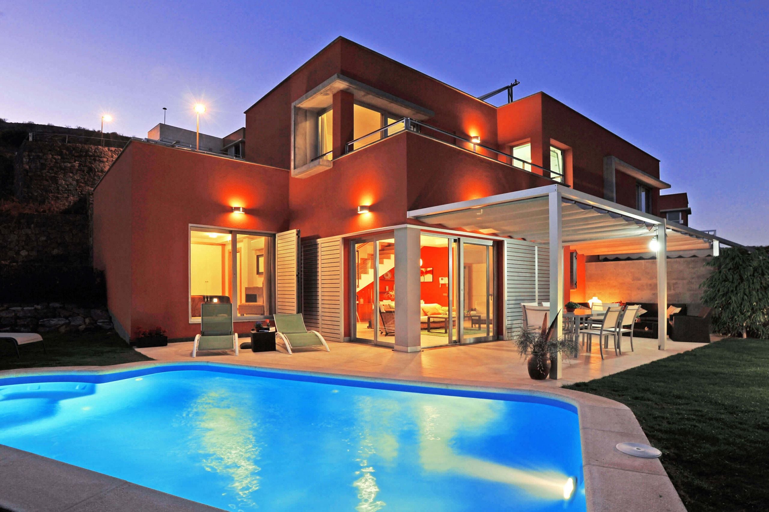 A modern two-story house with a swimming pool, outdoor seating area, and a covered patio.