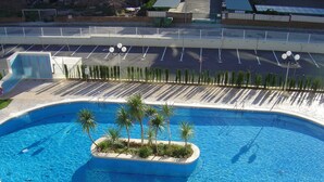 Une piscine avec une petite île au centre, entourée de palmiers.