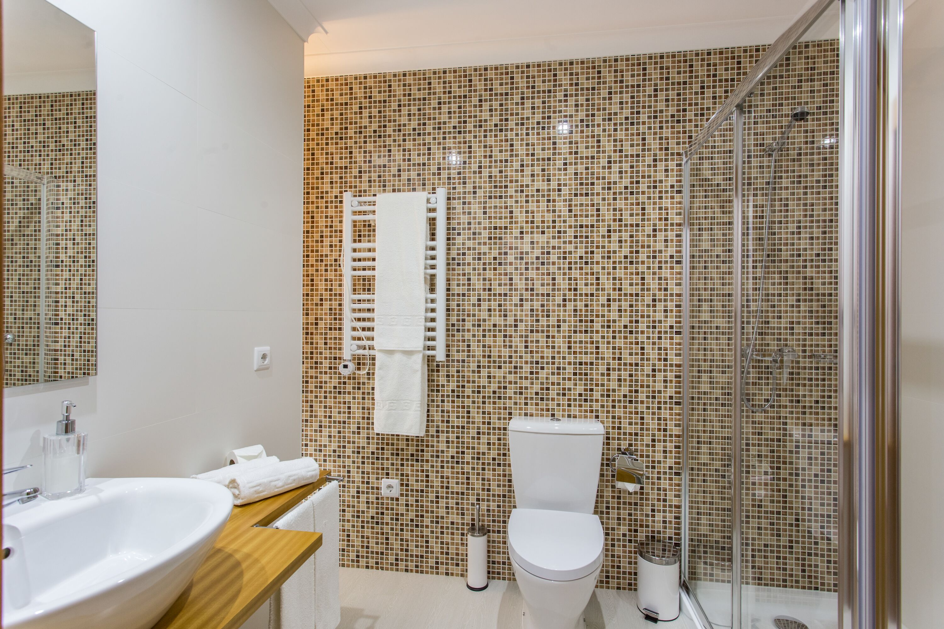 A modern bathroom with a large sink, toilet, and glass shower enclosure.