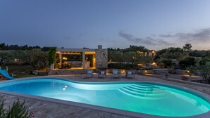 A swimming pool with a stone deck, lounge chairs, and a stone structure with lights. - Hacienda NOA/secluded estate/practice golf/enjoy the view and great pool (Grohote, Island of Šolta)