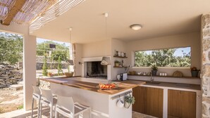 A modern kitchen with a central island, bar stools, a stone wall, and a view of the outdoors. - Hacienda NOA/secluded estate/practice golf/enjoy the view and great pool (Grohote, Island of Šolta)