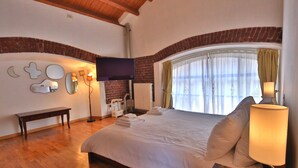 A bedroom with a large bed, a bench, a TV, and a window with curtains. - Loft by KlabHouse w/3BDRM+3BTH+Jacuzzi and Parking near Fond. Prada  (Milano)