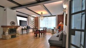 A spacious living room with a fireplace, a television, and a dining area with a table and chairs. - Loft by KlabHouse w/3BDRM+3BTH+Jacuzzi and Parking near Fond. Prada  (Milano)