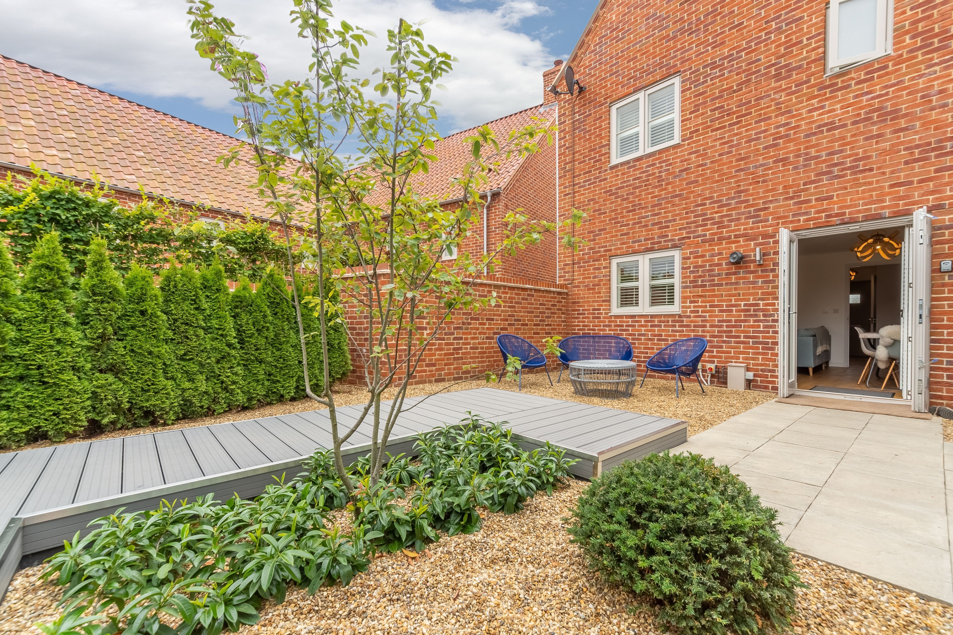 A brick building with a patio area, outdoor seating, and a small garden.