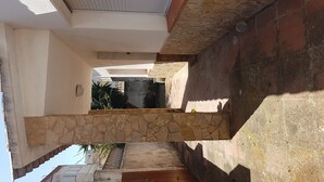 A narrow corridor with stone walls and a wooden door at the end. - HOLIDAY RENTAL HOUSE WITH GARDEN IN PALAMOS (Palamos)