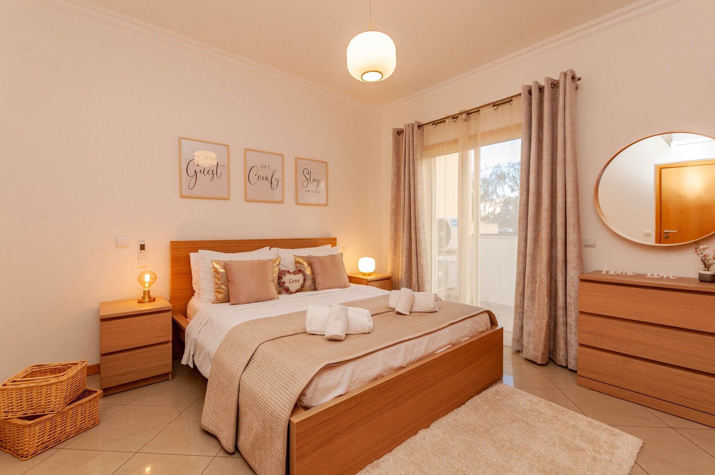 Een slaapkamer met een bed, nachtkastjes, een spiegel en een raam met gordijnen.