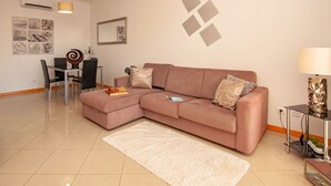 Een moderne woonkamer met een hoekbank, een eettafel met stoelen, een witte vloerkleed en een decoratieve lamp.