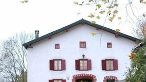 Un edificio blanco con contraventanas rojas y un techo muy inclinado.