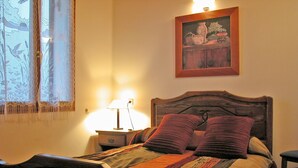 Una cama con un edredón estampado, una lámpara de noche y un cuadro en la pared.