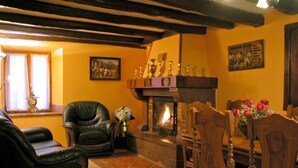 Una sala de estar acogedora con chimenea, sillones de cuero, una mesa de comedor de madera y un reloj en la pared.