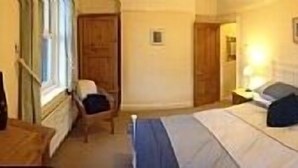 A hotel room with a bed, bedside tables, a window, and a door. - House within Conwy Castle Walls (Conwy)