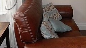 A brown leather sofa with patterned cushions against a plain wall. - House within Conwy Castle Walls (Conwy)