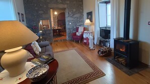 Un salon chaleureux avec un mur en pierre, une cheminée, un canapé, une table basse et une lampe.
