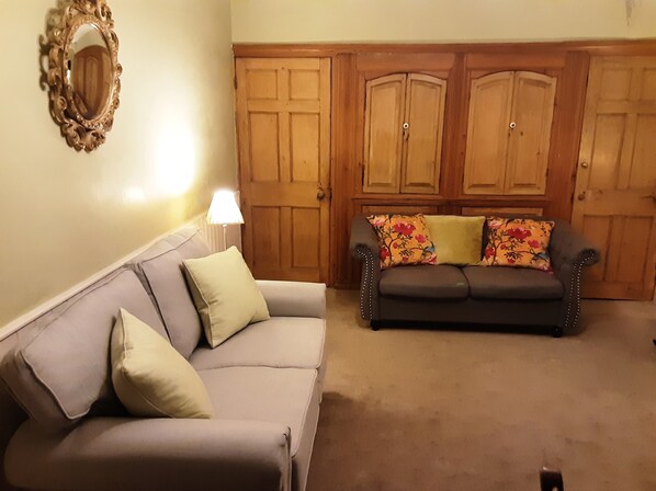 A living room with two sofas, a mirror, and wooden doors.