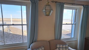A cozy room with a sofa and two windows offering a view of a beach. - 18th Century Cottage On Waterfront, Panoramic Sea Views, Courtyard Garden (Appledore, nr Bideford)