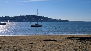A beach with a boat in the water, a sandy shore, and a distant hill with buildings. - 18th Century Cottage On Waterfront, Panoramic Sea Views, Courtyard Garden (Appledore, nr Bideford)