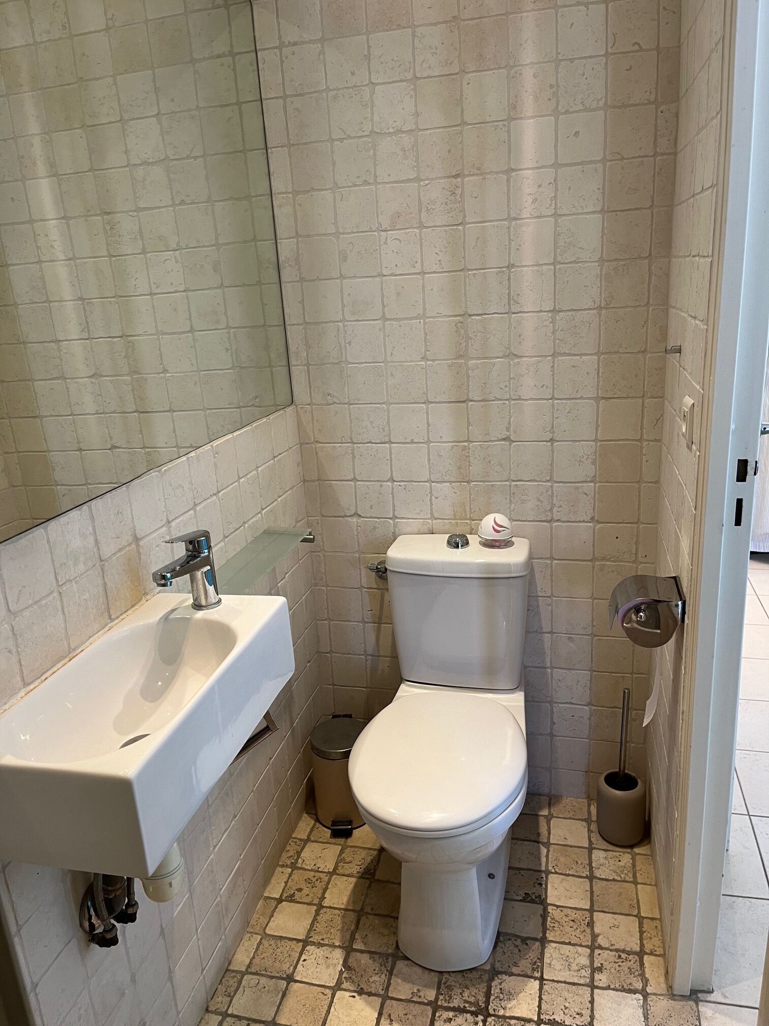 A small bathroom with a white sink, toilet, and a mirror.