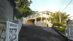 Un edificio a due piani con un balcone, un muro in pietra e un ingresso con cancello.