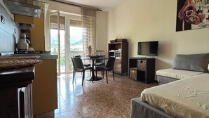 A hotel room with a bed, a desk, a chair, a television, and a ceiling fan.