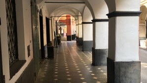 A corridor with arches, tiled flooring, and columns.