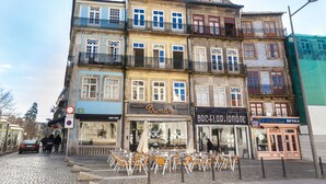 Un immeuble à plusieurs étages abritant une boulangerie nommée « Brimar » au rez-de-chaussée, une pharmacie au deuxième étage et un magasin d’optique au troisième étage.
