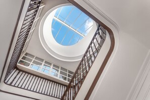 Experience the contemporary style with a circular skylight and a wooden staircase leading to an upper level with large windows.