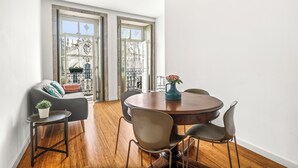Un coin repas avec une table ronde, quatre chaises, une plante en pot et une vue dégagée grâce à de grandes fenêtres.