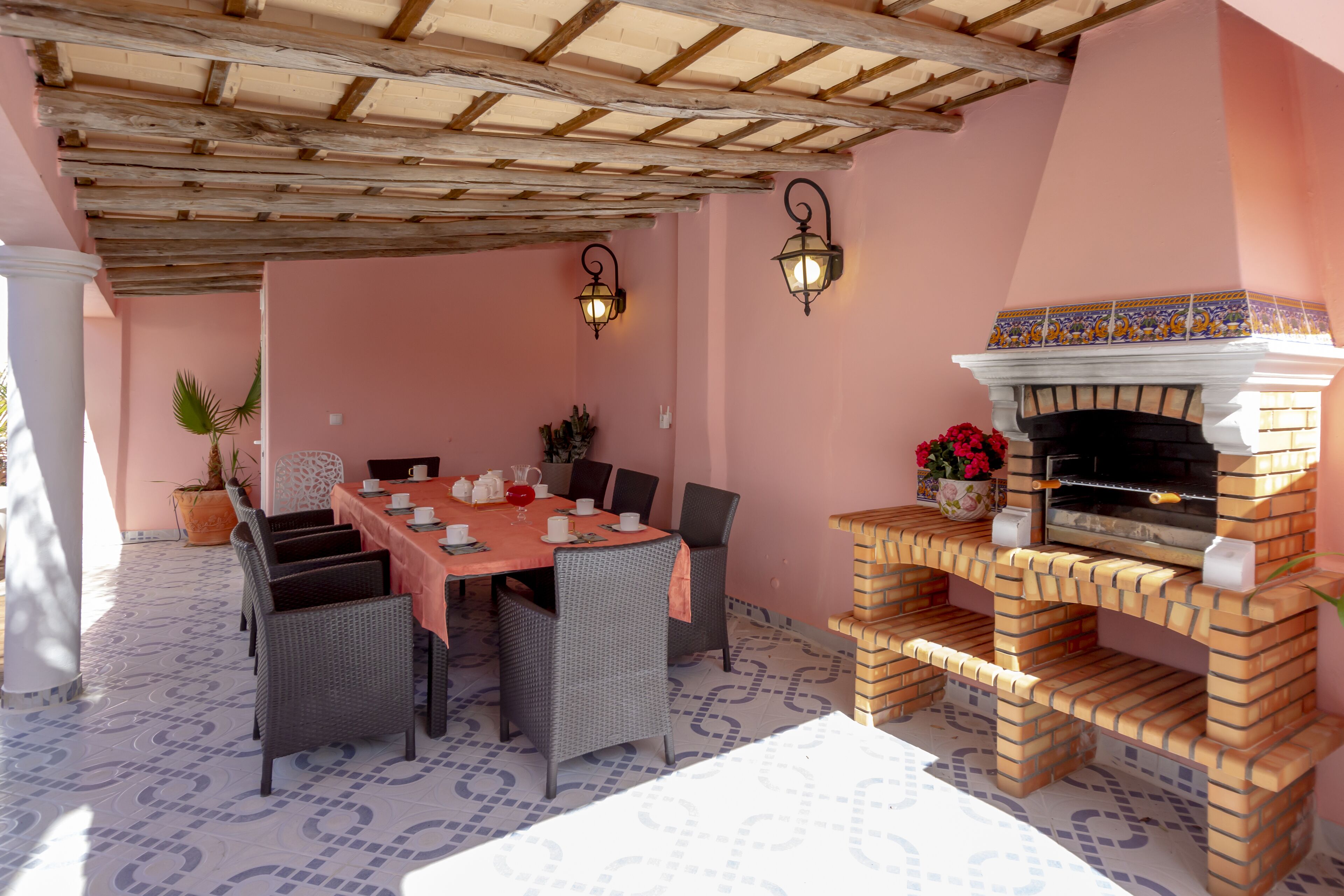 A dining area with a brick oven, wicker chairs, and a table set for four.
