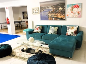 A teal sofa with floral and tropical patterned cushions, a glass coffee table with decorative items, and a floral-patterned rug. - Villa Beach Palace Luxury 5 Bed Villa w/heatable
Pool, Jacuzzi, 500m Beach AC (Armação de Pêra)