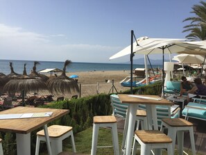 Ein Restaurant direkt am Strand mit Außenbereich, Blick auf den Strand und Sonnenschirmen.